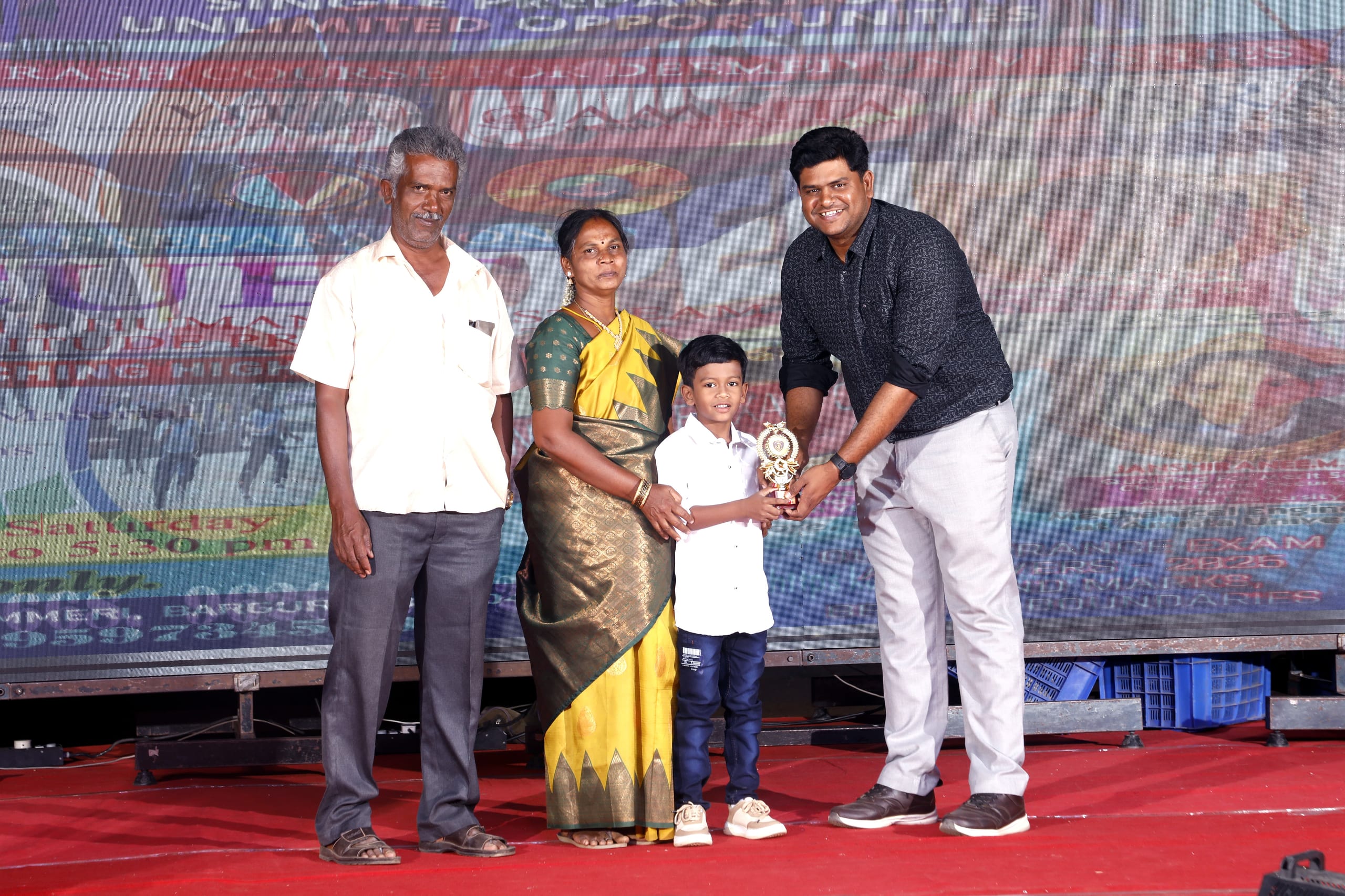 Young student receiving an award on stage with family