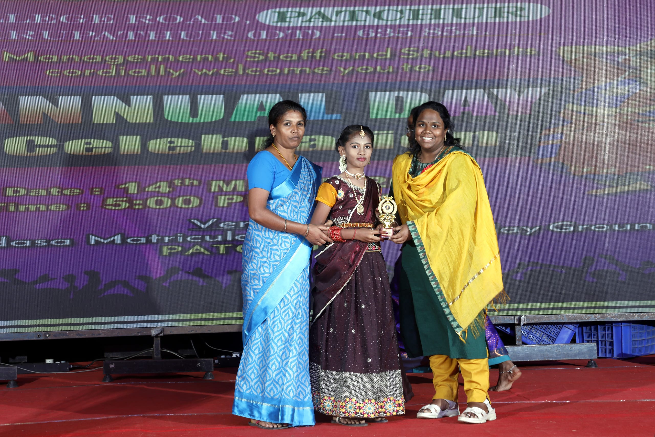 Girls standing with a trophy during annual day awards