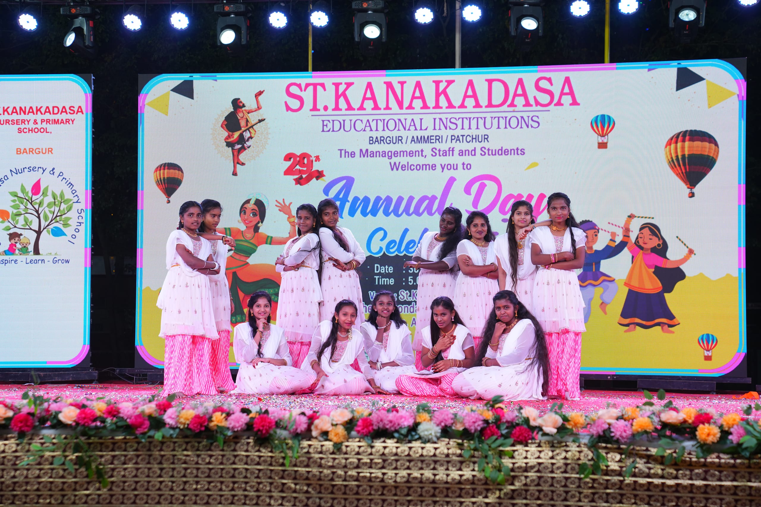 Students posing on stage before an annual day banner