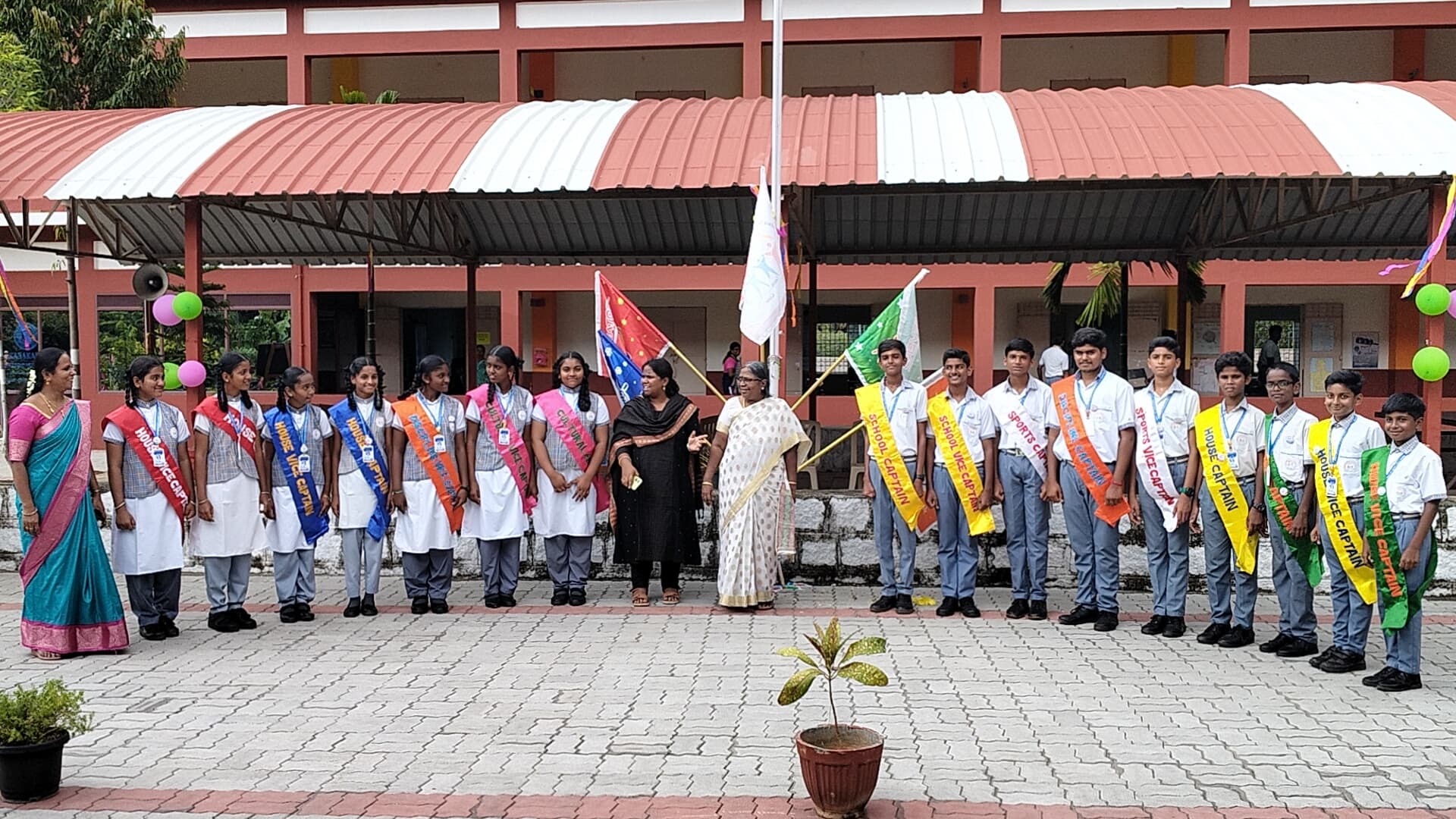Student council members standing with staff near the flagpole