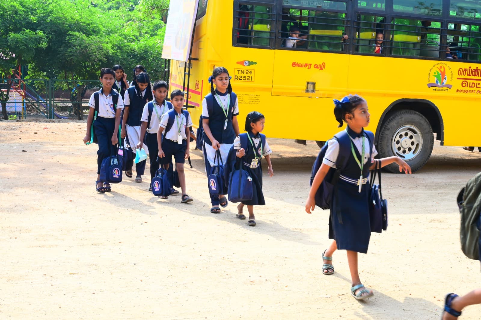 Students walking from the school bus with their bags